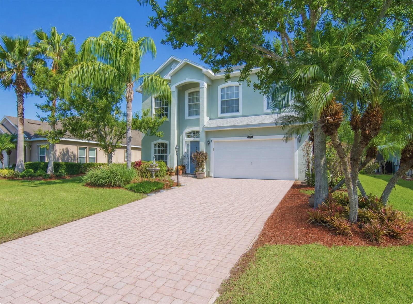 A two-story light green house with a white garage and a paved driveway — 521 N Valencia Circle SW, Vero Beach FL 32968, VERO BEACH, FL