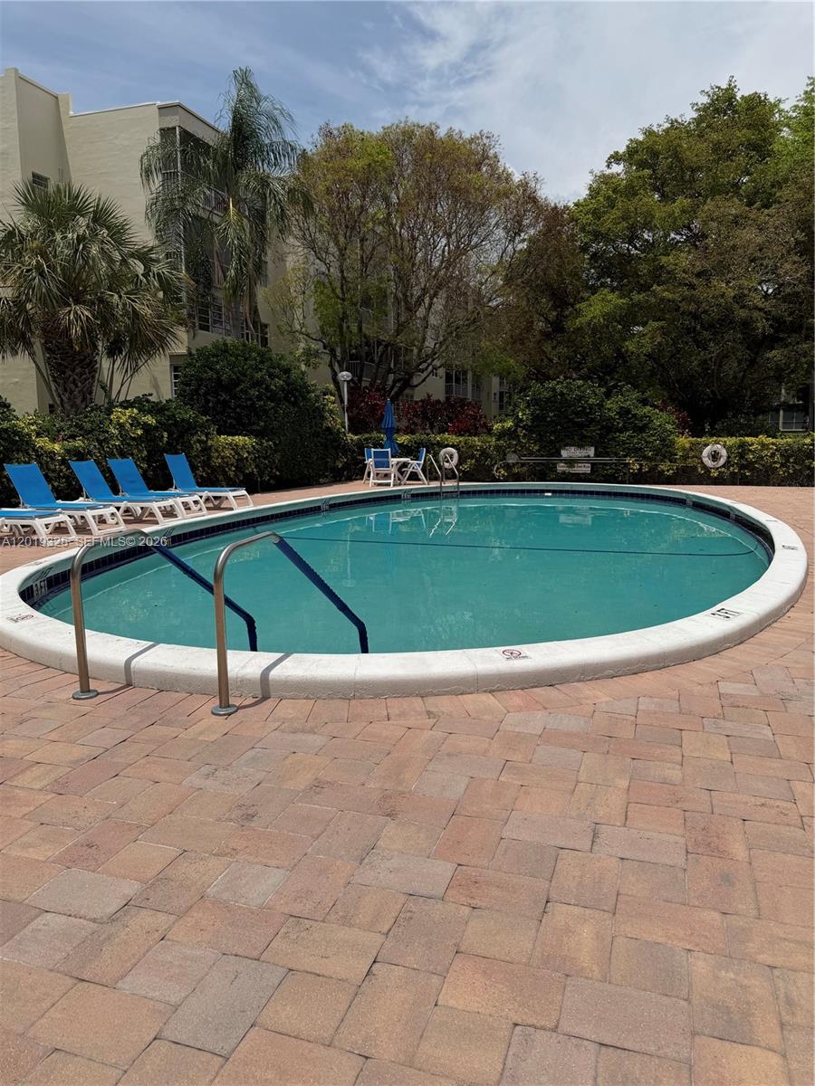 An outdoor swimming pool with blue lounge chairs on a brick patio — 6701 Cypress Rd # 109, Plantation FL 33317, PLANTATION, FL