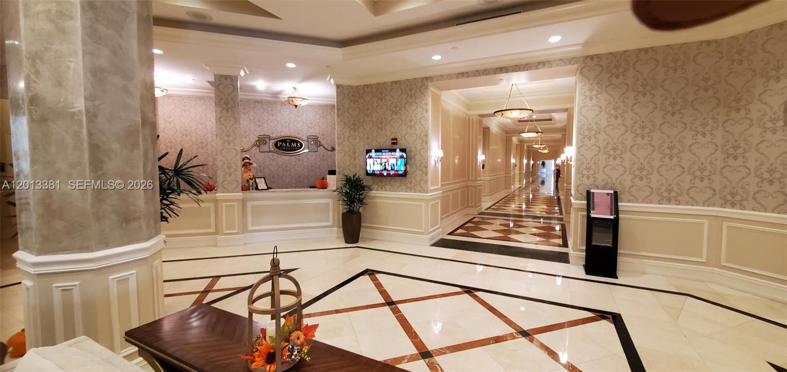 The lobby features a reception desk, patterned wallpaper, marble floors, and a long hallway — 16102 Emerald Estates Dr # 428, Weston FL 33331, WESTON, FL