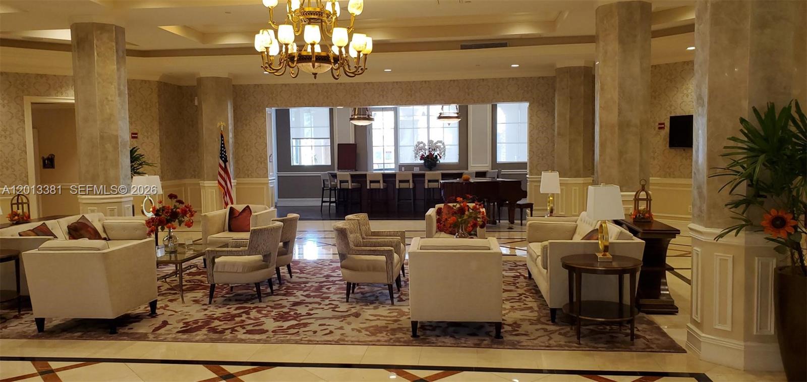 A spacious lobby features a large chandelier, plush seating areas, and a bar in back — 16102 Emerald Estates Dr # 428, Weston FL 33331, WESTON, FL