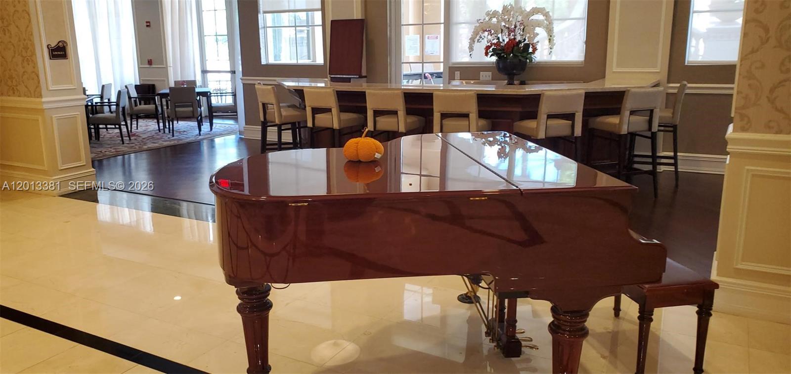A grand piano sits in a room with a bar, seating area, and tile floors — 16102 Emerald Estates Dr # 428, Weston FL 33331, WESTON, FL
