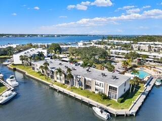 An aerial view shows a multi-story waterfront apartment complex with boat slips and a pool — 1950 SW Palm City Road # 9102, Stuart FL 34994, STUART, FL