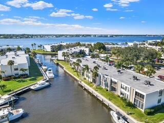 An aerial view shows multi-story apartment buildings situated along a canal with docked boats — 1950 SW Palm City Road # 9102, Stuart FL 34994, STUART, FL