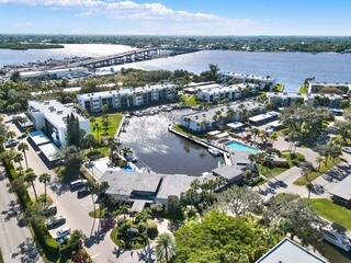 An aerial view of a waterfront condominium complex with a central marina and nearby bridge — 1950 SW Palm City Road # 9102, Stuart FL 34994, STUART, FL