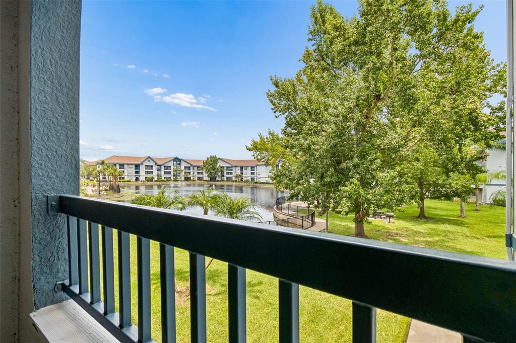 A view from a balcony overlooking a pond, green lawn, and apartment buildings — 1640 VILLA CAPRI CIRCLE UNIT 208, ODESSA, FL