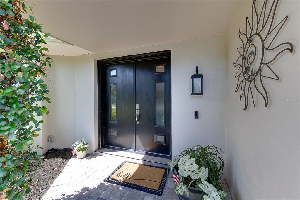 A black double front door with glass inserts sits under a covered entryway — 13650 96TH TERRACE, SEMINOLE, FL