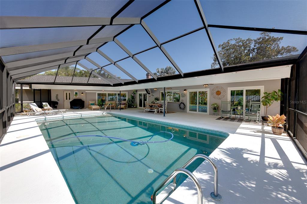 A swimming pool with a screen enclosure sits on a patio next to a house — 13650 96TH TERRACE, SEMINOLE, FL