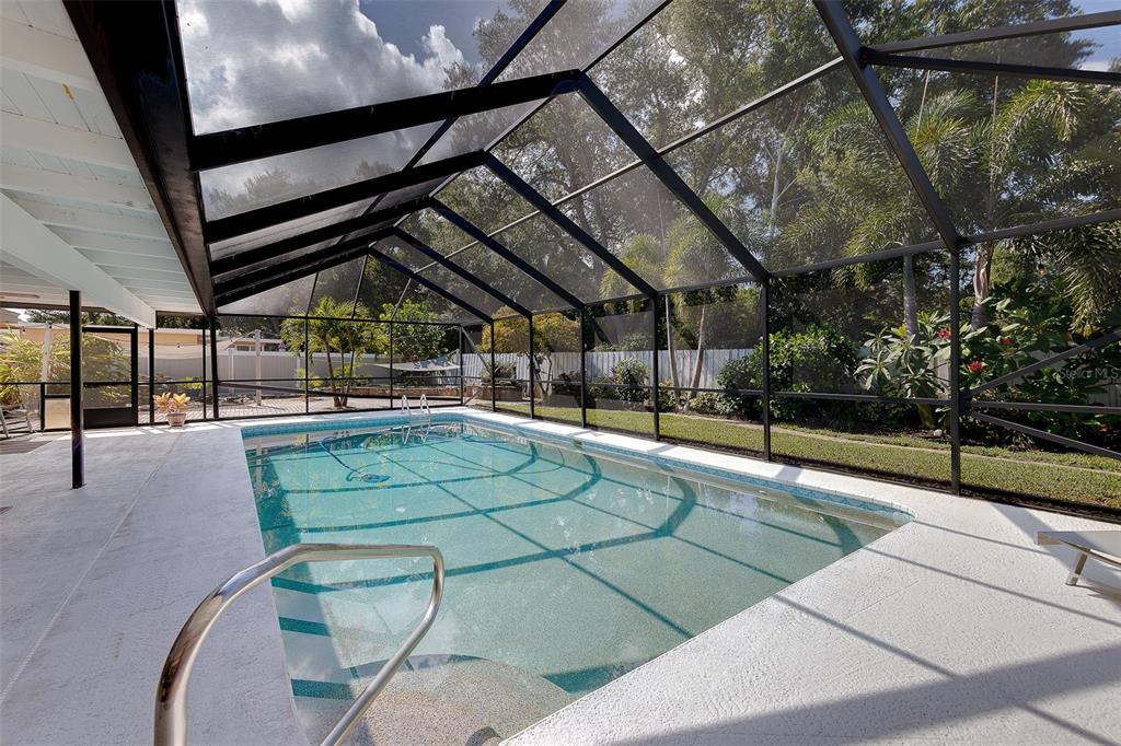 A rectangular swimming pool is enclosed by a screened lanai with a white concrete deck — 13650 96TH TERRACE, SEMINOLE, FL