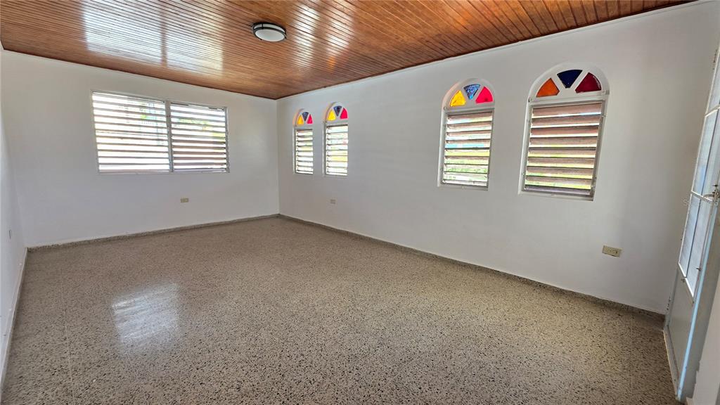 An empty room features a wood-paneled ceiling, terrazzo flooring, and arched windows with stained glass — PR 922 KM 0.4 BO. COLLORES, LAS PIEDRAS, PR