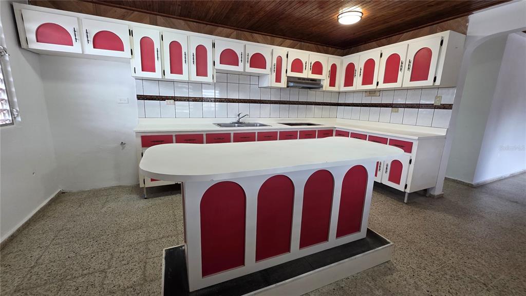 A kitchen features white cabinets with red arched panels, a white island, and tiled walls — PR 922 KM 0.4 BO. COLLORES, LAS PIEDRAS, PR