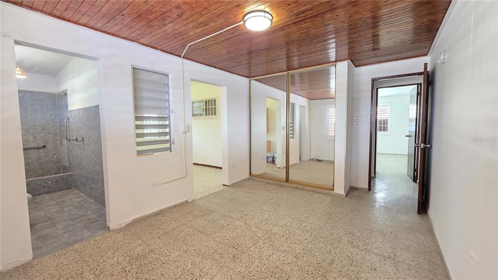 A bedroom with a wood-paneled ceiling, mirrored closet doors, and an attached tiled bathroom — PR 922 KM 0.4 BO. COLLORES, LAS PIEDRAS, PR