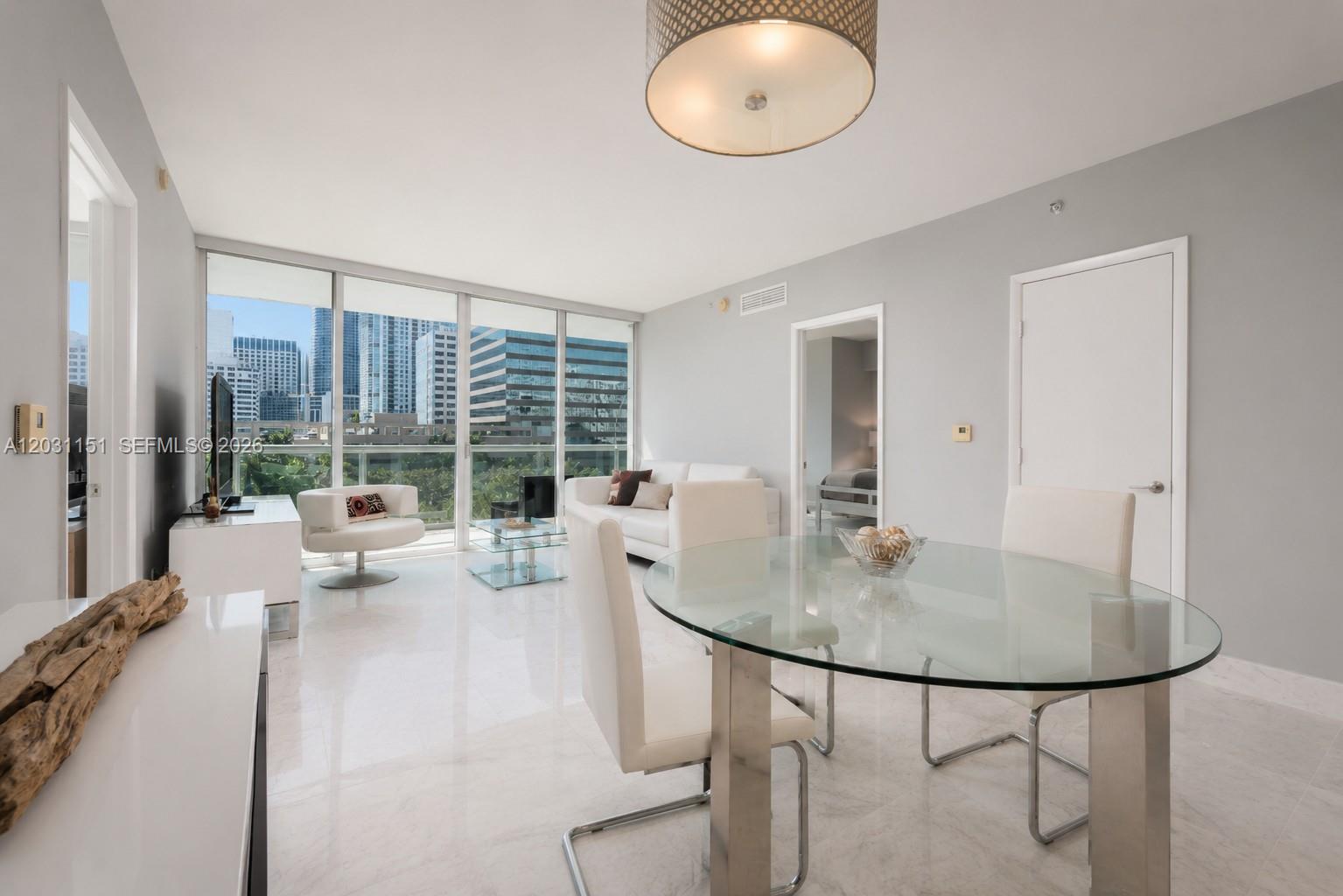 A bright living and dining area features white tile floors, glass furniture, and floor-to-ceiling windows — 495 Brickell Ave # 705, Miami FL 33131, MIAMI, FL