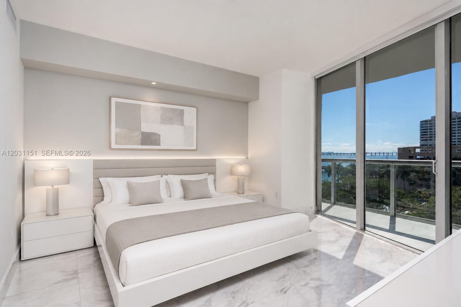 A modern bedroom features a platform bed, marble floors, and a balcony with water views — 495 Brickell Ave # 705, Miami FL 33131, MIAMI, FL