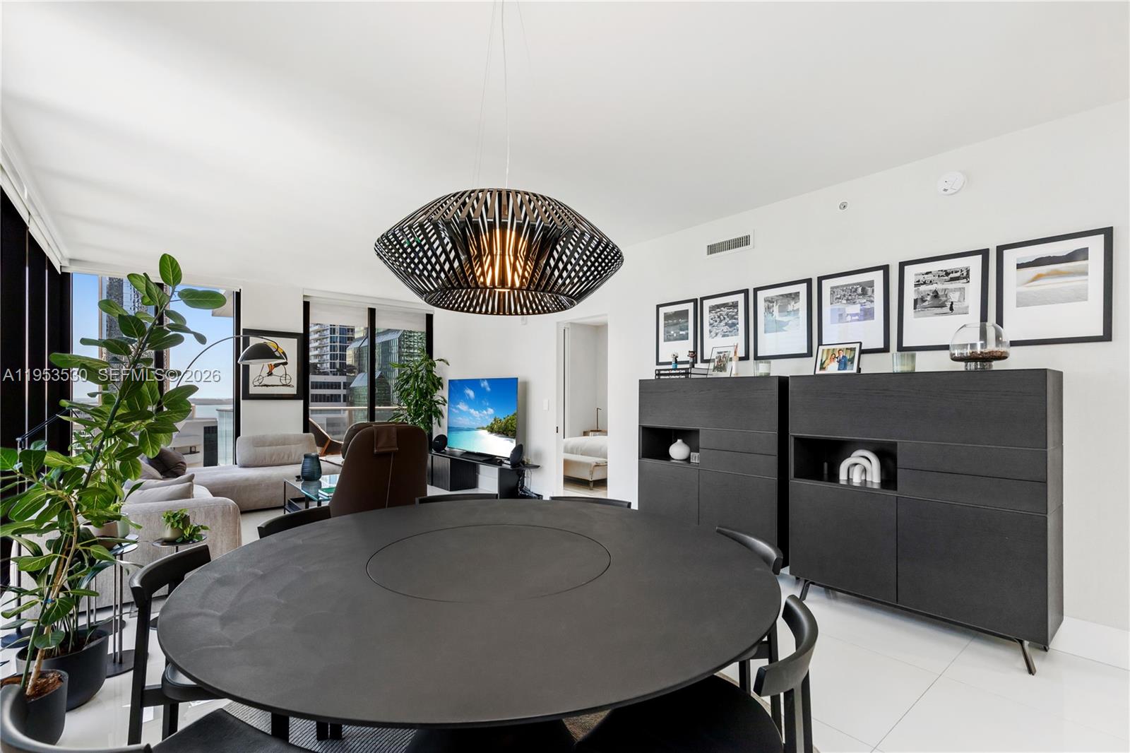 A modern dining room features a large round black table, pendant lighting, and dark cabinetry — 1010 Brickell Ave # 1701, Miami FL 33131, MIAMI, FL