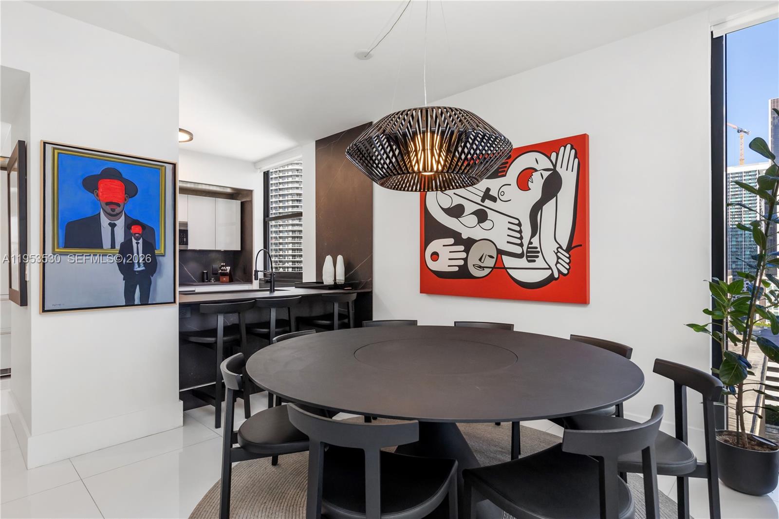 A dining area features a round black table, modern chairs, and two large art pieces — 1010 Brickell Ave # 1701, Miami FL 33131, MIAMI, FL