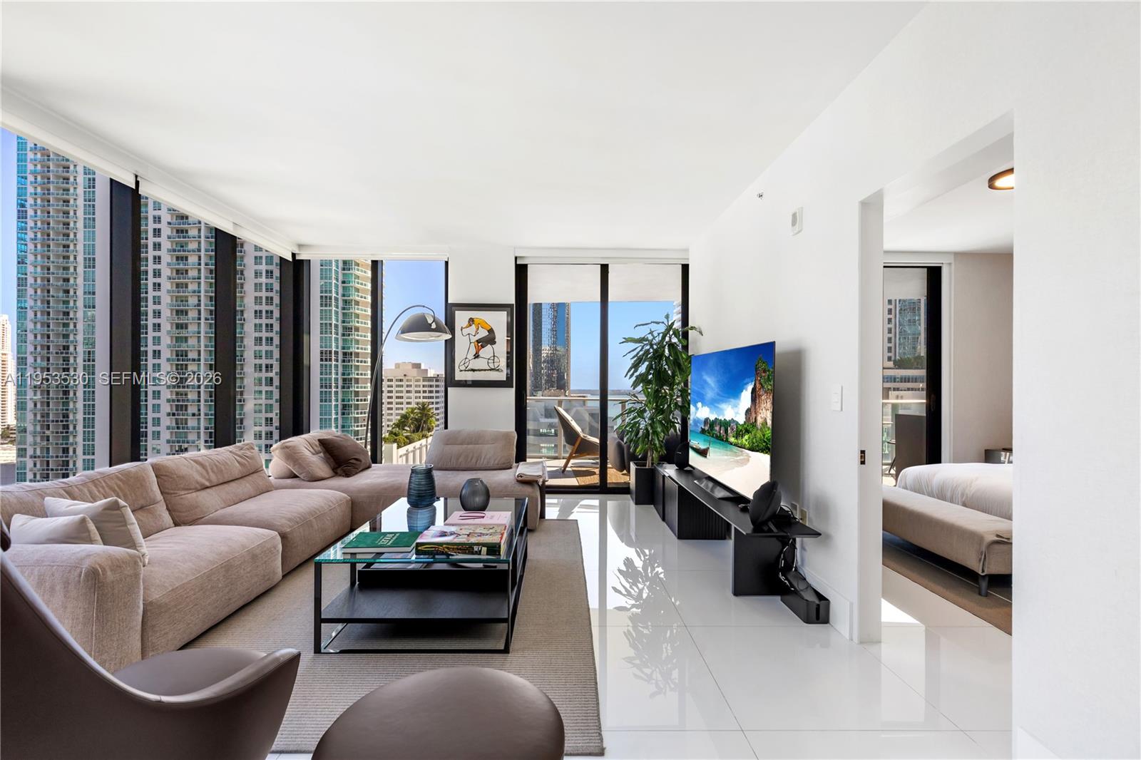 A modern living room features white tile floors, a beige sectional sofa, and floor-to-ceiling windows — 1010 Brickell Ave # 1701, Miami FL 33131, MIAMI, FL