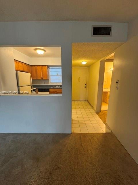 A view from a carpeted room looking into a kitchen and a tiled hallway — 6505 Winfield Blvd # 51, Margate FL 33063, MARGATE, FL