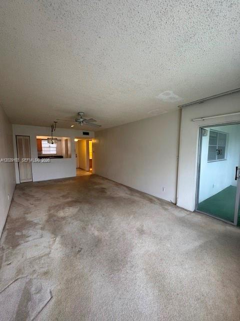An empty living room with beige carpeting, a ceiling fan, and a sliding glass door — 6505 Winfield Blvd # 51, Margate FL 33063, MARGATE, FL
