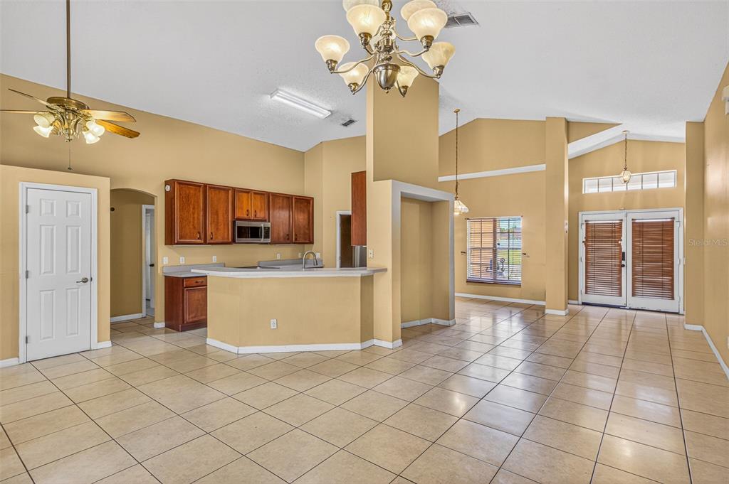 A kitchen with wood cabinets and a breakfast bar opens into a large tiled room — 1000 ROYAL MARQUIS CIRCLE, OCOEE, FL