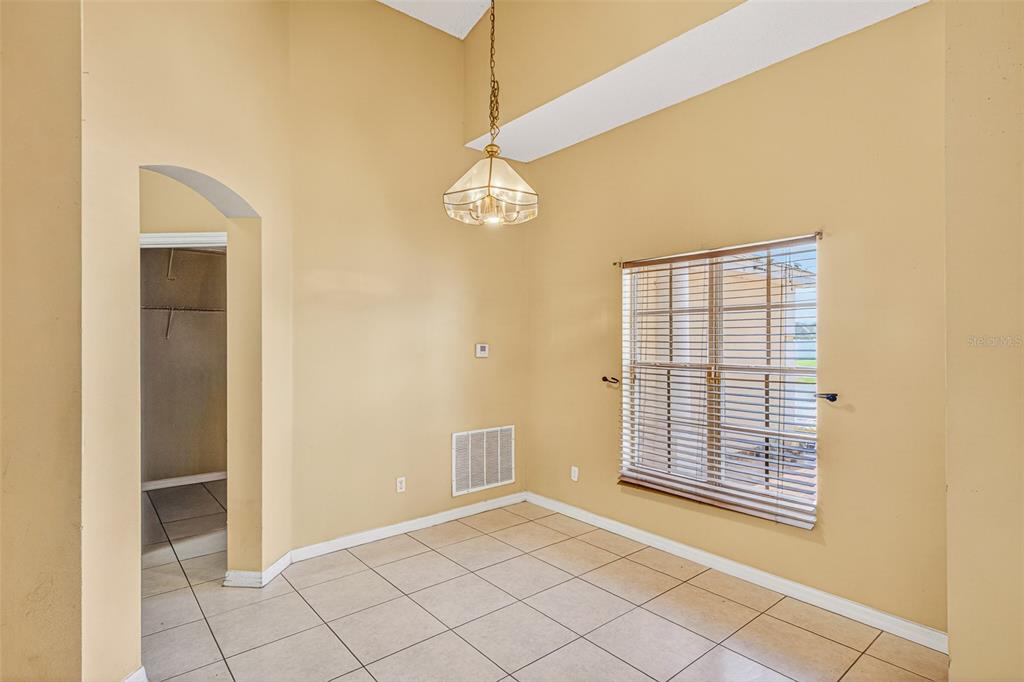 A dining area with beige walls, tile flooring, a vaulted ceiling, and a hanging light fixture — 1000 ROYAL MARQUIS CIRCLE, OCOEE, FL