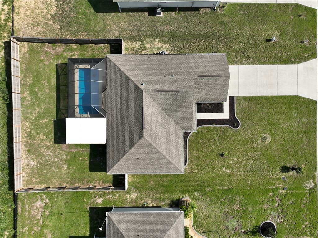 An aerial view shows a house with a shingled roof, a pool enclosure, and a driveway — 513 CENTRAL RIDGE LANE, FROSTPROOF, FL