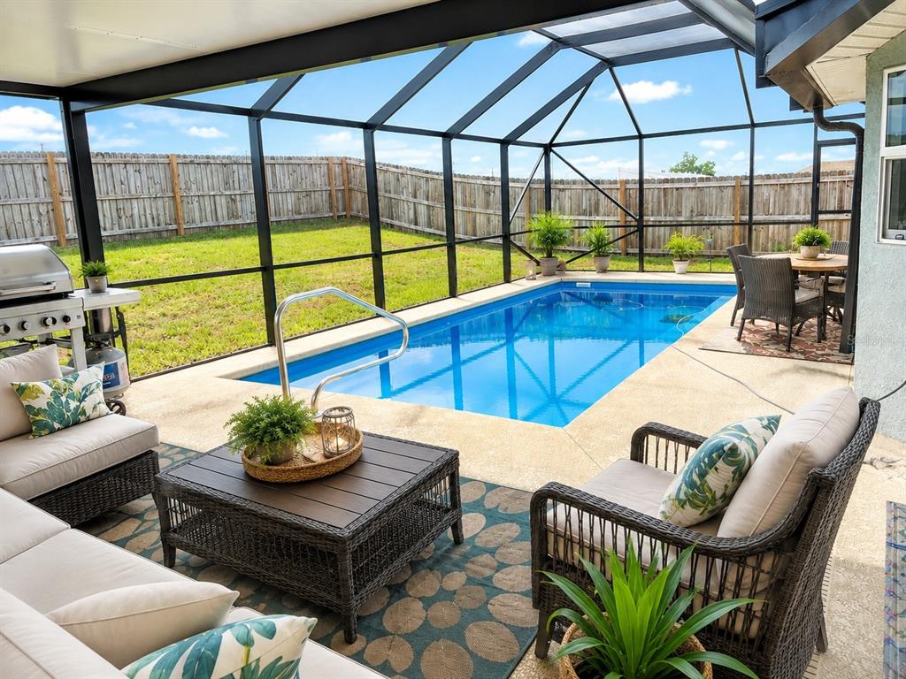 A screened-in patio features a swimming pool, outdoor seating, and a grill — 513 CENTRAL RIDGE LANE, FROSTPROOF, FL