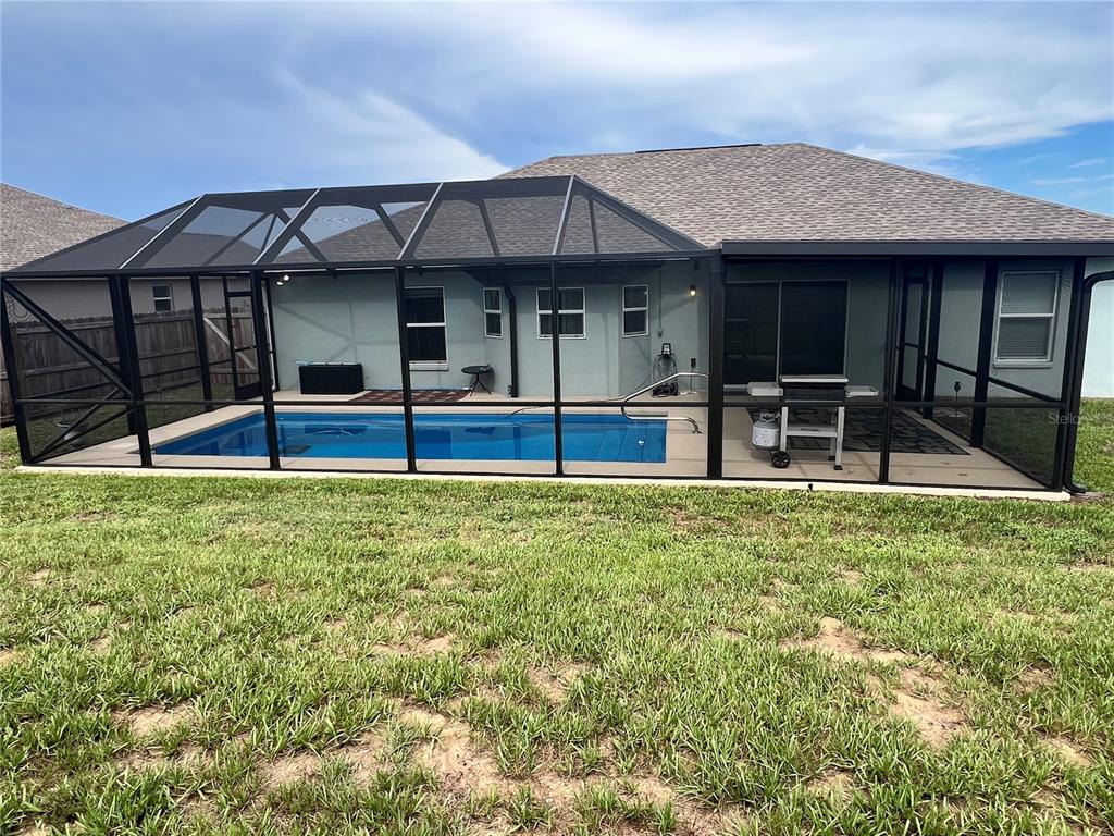 A backyard view of a house with a screened-in pool and patio area — 513 CENTRAL RIDGE LANE, FROSTPROOF, FL