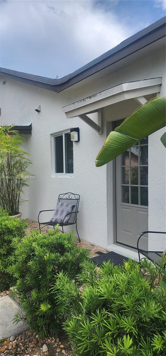 A white stucco exterior features a gray door, a small window, and a metal chair — 12641 SW 210th Ter # A, Miami FL 33177, MIAMI, FL