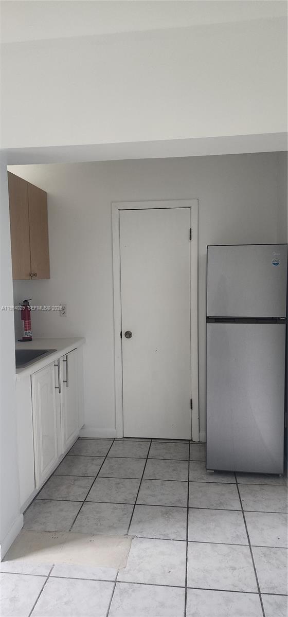 A kitchen features white cabinets, a stainless steel refrigerator, and light-colored floor tiles — 12641 SW 210th Ter # A, Miami FL 33177, MIAMI, FL
