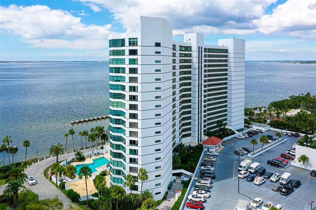An aerial view of a tall white residential building next to a pool and parking lot — 888 BOULEVARD OF THE ARTS UNIT 505, SARASOTA, FL
