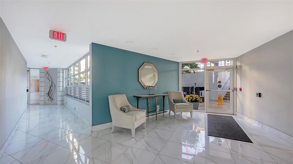 A bright lobby features white marble floors, a teal accent wall, and two armchairs — 888 BOULEVARD OF THE ARTS UNIT 505, SARASOTA, FL