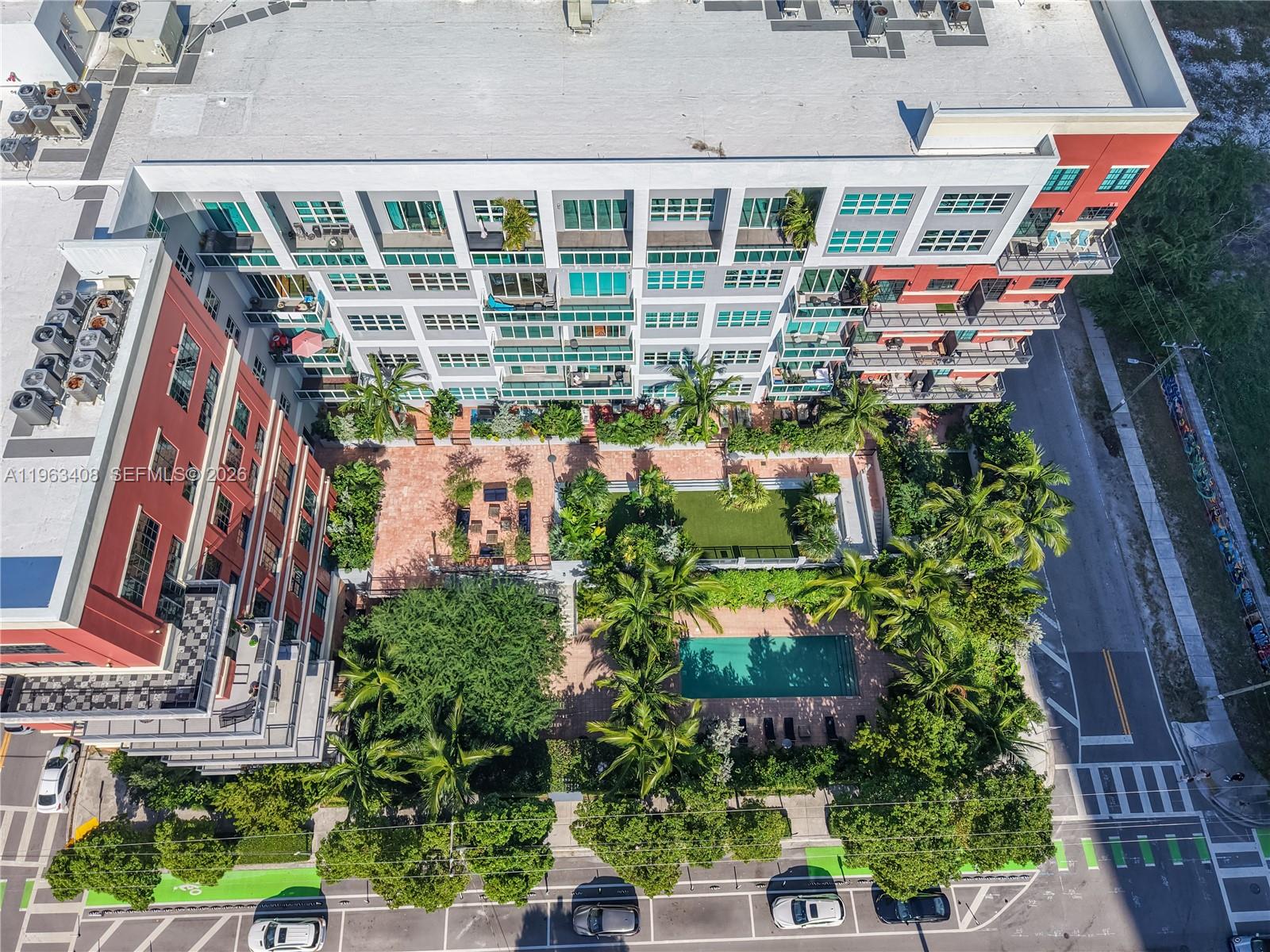 An aerial view shows a multi-story apartment building with a central courtyard, pool, and landscaping — 1749 NE Miami Ct # 605, Miami FL 33132, MIAMI, FL