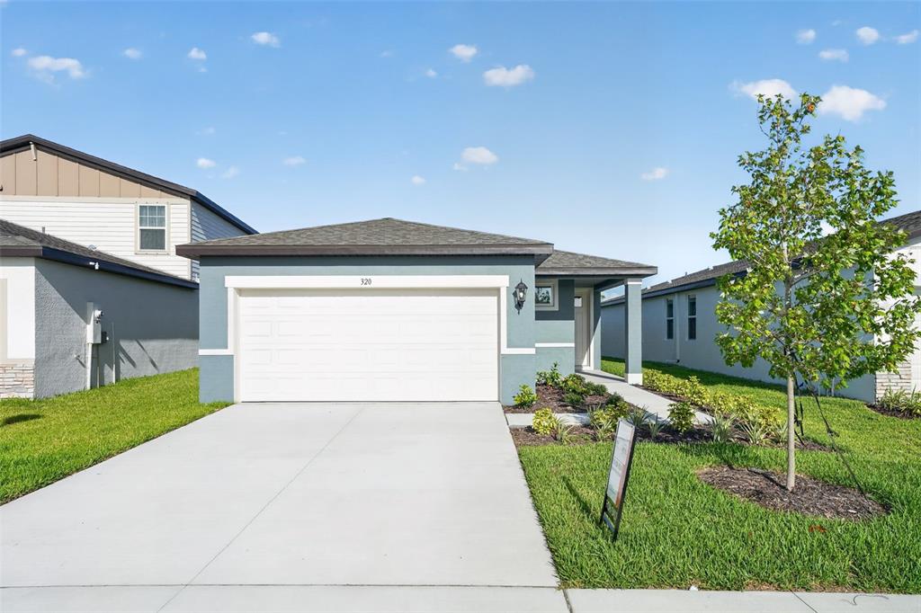 A single-story house with a blue exterior, a two-car garage, and a front lawn — 320 LAZY SHORE DRIVE, NOKOMIS, FL