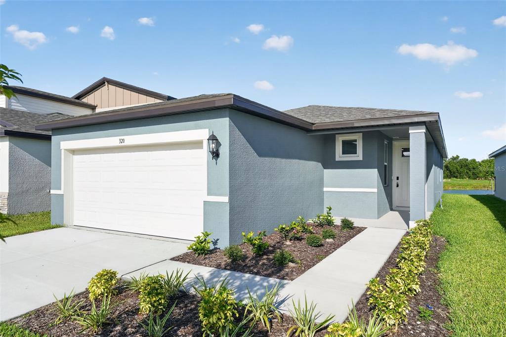 A single-story house with a blue stucco exterior, a two-car garage, and a concrete walkway — 320 LAZY SHORE DRIVE, NOKOMIS, FL
