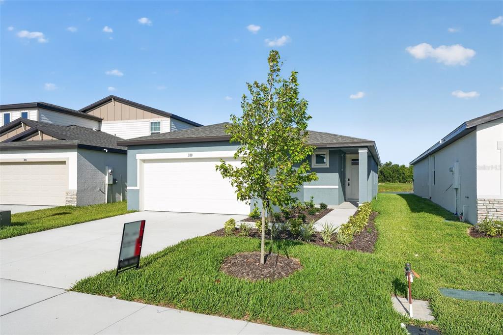 A single-story house with a white garage door, a small tree, and a grassy yard — 320 LAZY SHORE DRIVE, NOKOMIS, FL