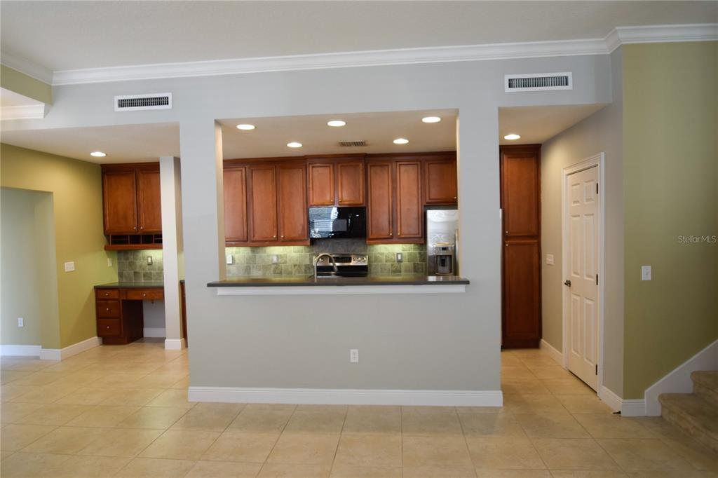 A kitchen with wood cabinets, dark countertops, and tile flooring viewed from an adjacent room — 1420 LAKE BALDWIN LANE, ORLANDO, FL