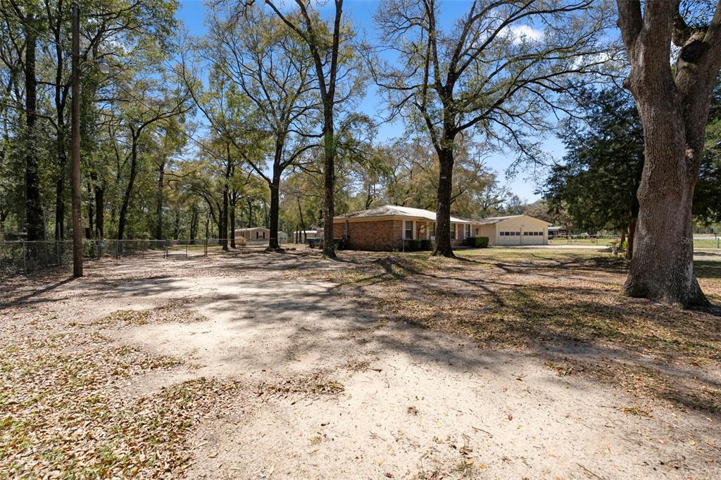 A large, sandy yard with mature trees leads to a brick house and detached garage — 1788 HIGHWAY 10A, PONCE DE LEON, FL
