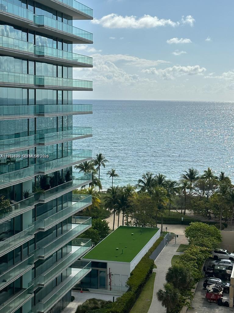 A high-rise building overlooks a beach, palm trees, and the ocean on a sunny day — 10185 Collins Ave # 1103, Bal Harbour FL 33154, BAL HARBOUR, FL