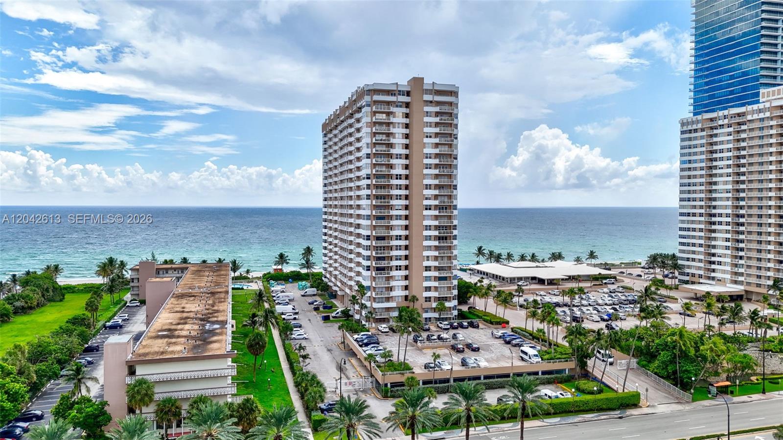 An aerial view shows high-rise apartment buildings near a beach with a parking lot — 1950 S Ocean DR. # 6B, Hallandale Beach FL 33009, HALLANDALE BEACH, FL