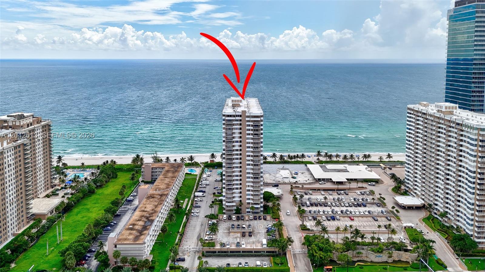An aerial view shows a tall residential building on a beach with a red arrow — 1950 S Ocean DR. # 6B, Hallandale Beach FL 33009, HALLANDALE BEACH, FL