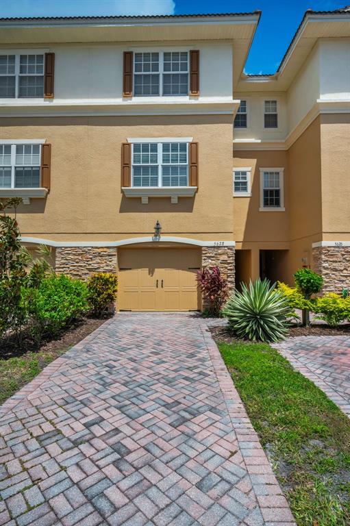 A tan townhouse exterior features a paved driveway, a single-car garage, and stone accents — 5628 SEA TURTLE COURT, NEW PORT RICHEY, FL