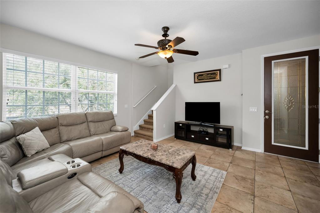 A living room features a beige sectional sofa, a marble coffee table, and tiled floors — 5628 SEA TURTLE COURT, NEW PORT RICHEY, FL