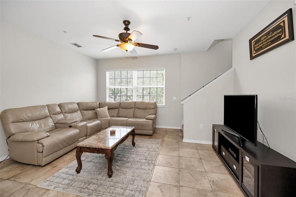 A living room features a beige sectional sofa, a marble-topped coffee table, and tile flooring — 5628 SEA TURTLE COURT, NEW PORT RICHEY, FL