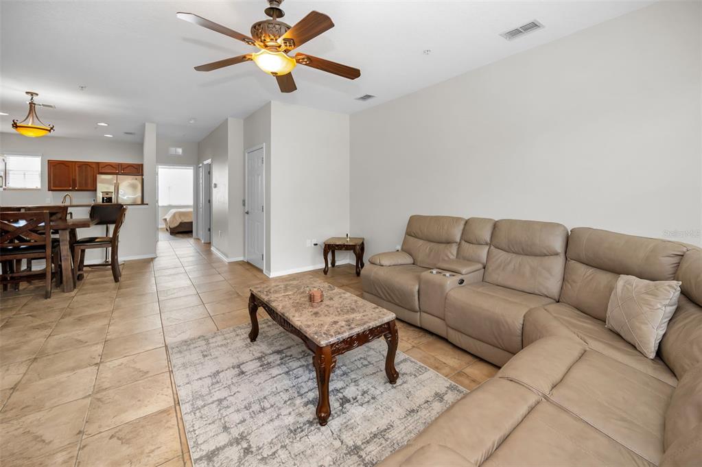 A living room with tile floors, a tan sectional sofa, and a marble-topped coffee table — 5628 SEA TURTLE COURT, NEW PORT RICHEY, FL