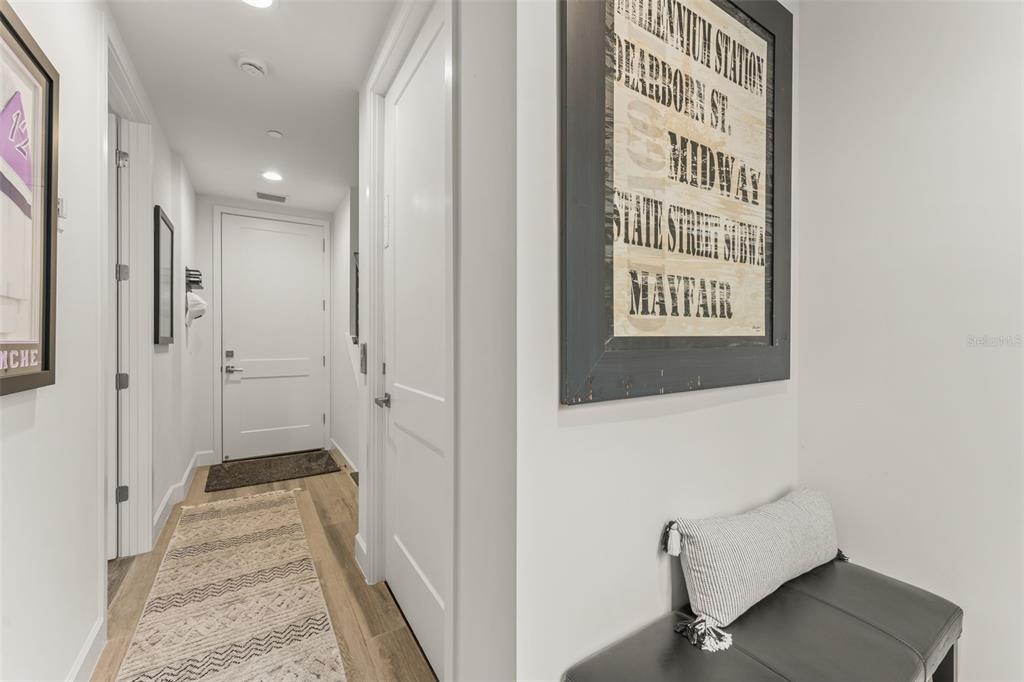 A hallway with light wood flooring, a white door, and a bench with a pillow — 131 OAK LAUREL DRIVE, WINTER GARDEN, FL