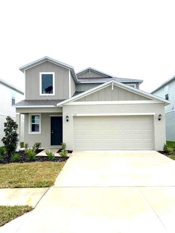 A two-story suburban house features a beige stucco exterior, a gray garage, and vertical siding — 11522 BRAE WAY, DADE CITY, FL