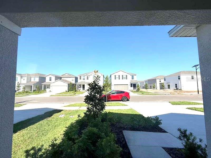 A view from a covered porch looking out at a suburban street with new houses — 11522 BRAE WAY, DADE CITY, FL