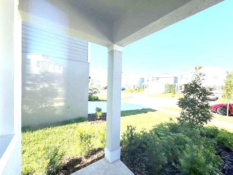 A view from a covered porch looking out toward a suburban street and neighboring houses — 11522 BRAE WAY, DADE CITY, FL