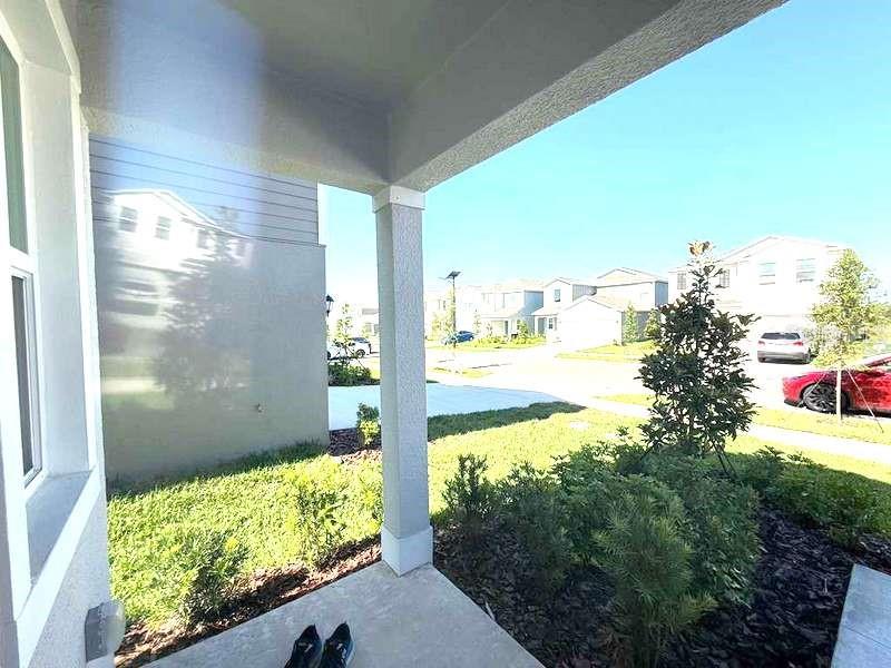 A view from a covered porch looking out toward a suburban street and neighboring houses — 11522 BRAE WAY, DADE CITY, FL