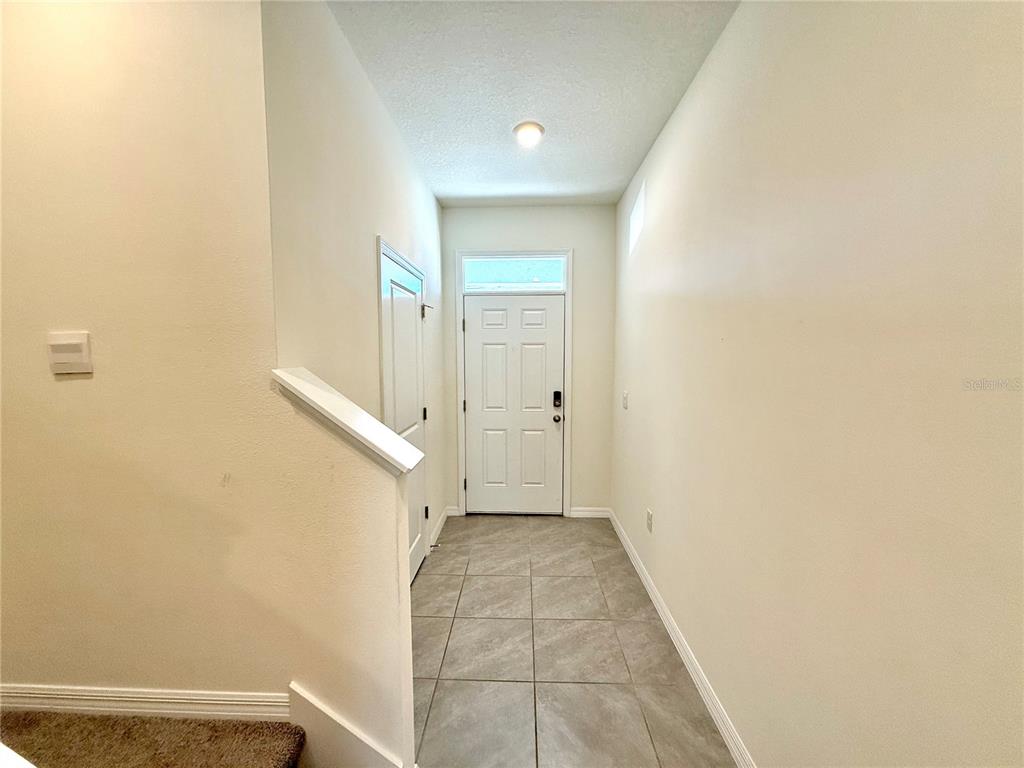 A tiled entryway features a white front door with a transom window and stairs nearby — 34309 SORREL MINT DRIVE, WESLEY CHAPEL, FL
